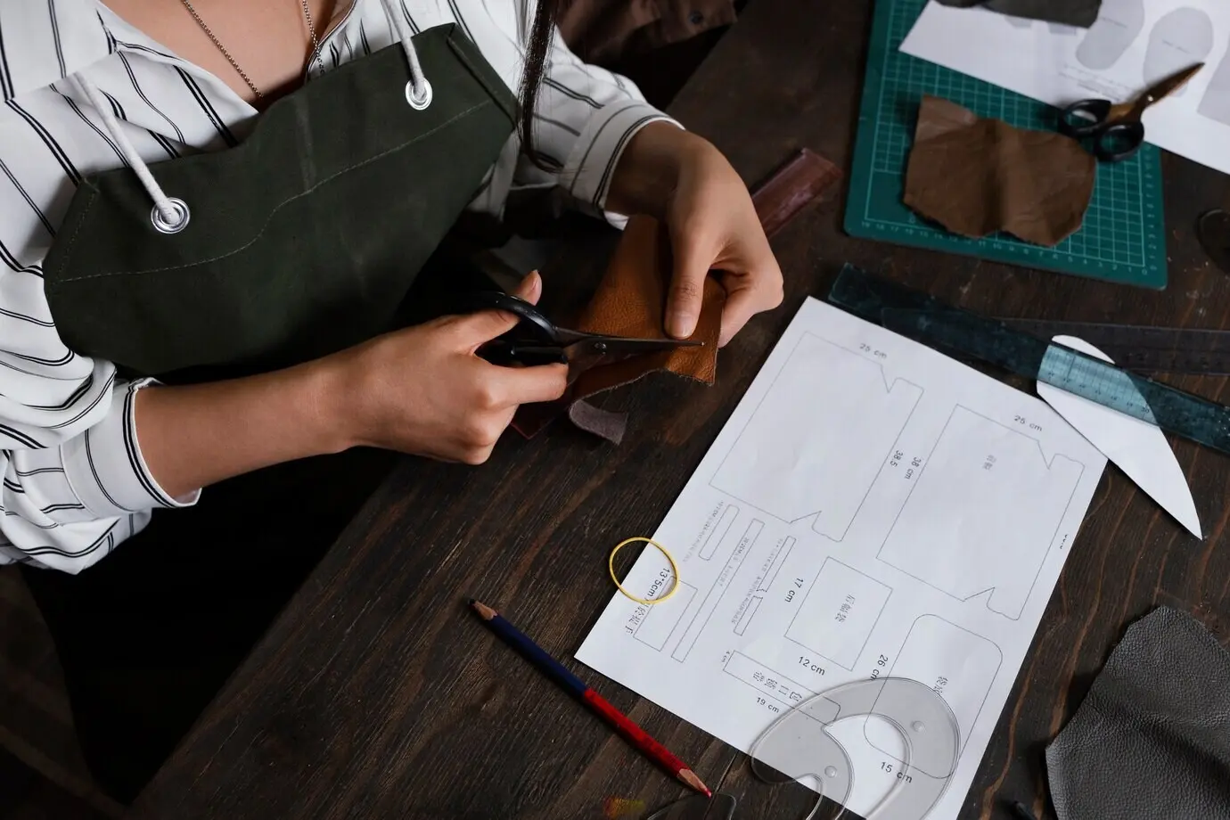 Nahaufnahme von Händen beim Schneiden von Stoff.